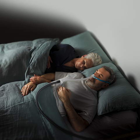 Couple asleep, man has sleep device